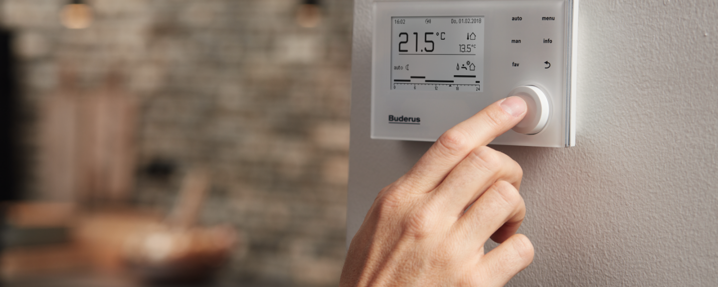 Un homme touche un thermostat Buderus
