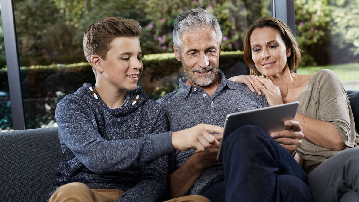 Family sitting on couch and looking at tablet