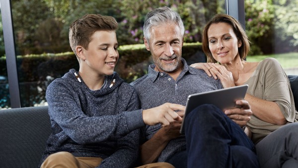 Family sitting on couch and looking at tablet
