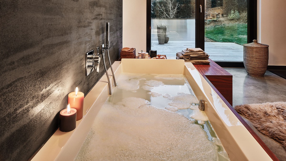 Moderná kúpeľňa s vaňou plnou horúcej vody so sviečkami