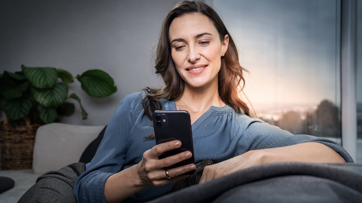 Mladá žena sediaca na sedačke s mobilom v ruke
