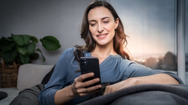 Mladá žena sediaca na sedačke s mobilom v ruke