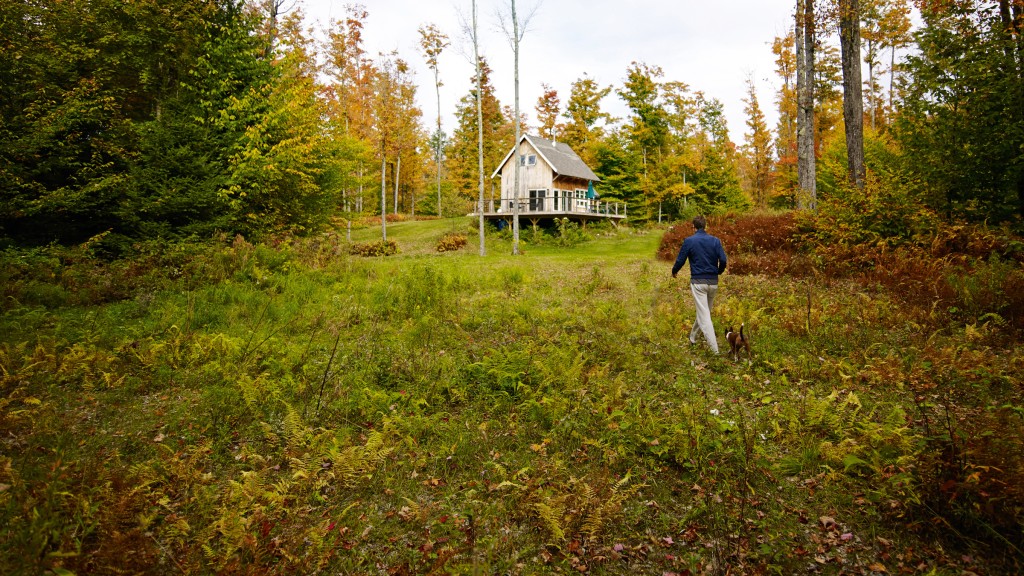 Muž kráčajúci k chate uprostred lesa