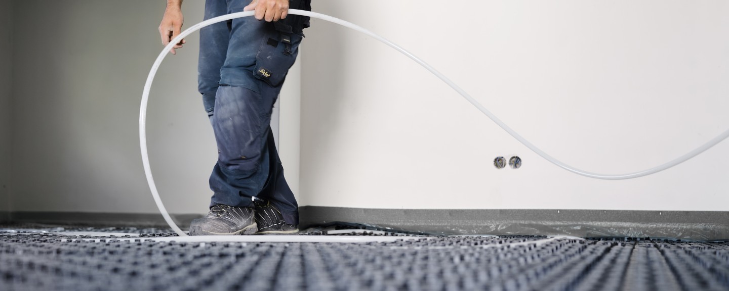 Muž ukladajúci hadice podlahového kúrenia